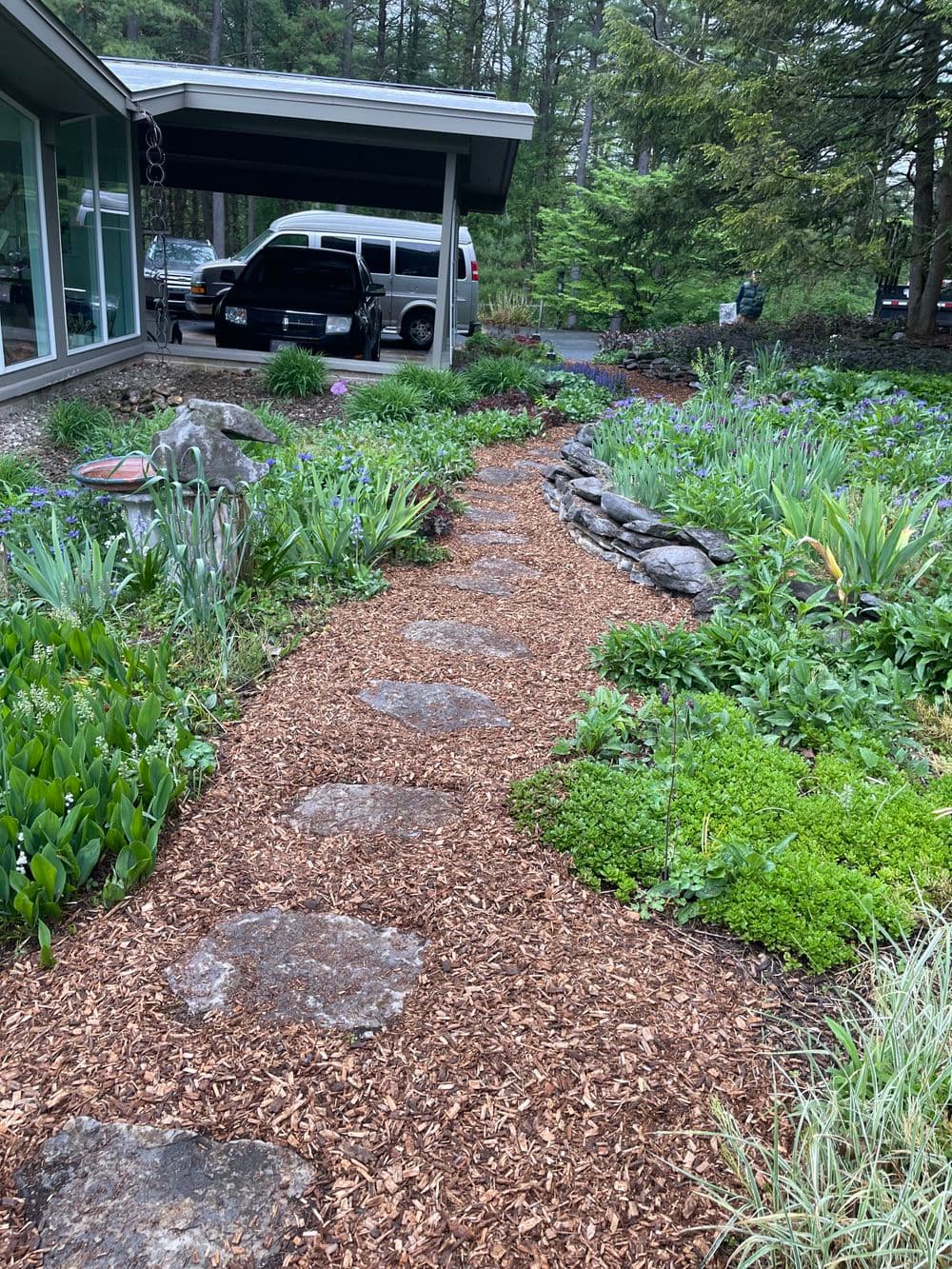 Stone pathway through a lush garden with colorful flowers and greenery.